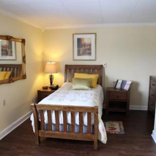 A cozy bedroom with a single bed, wooden furniture, and soft lighting.