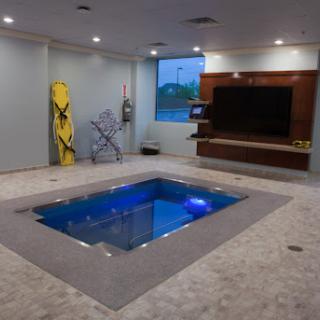 A stylish indoor pool integrated into a modern living space, featuring blue lighting and contemporary decor.