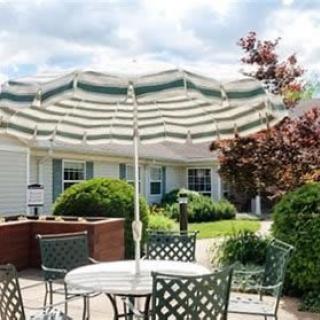 A cozy outdoor patio area with a table and chairs under a large striped umbrella.