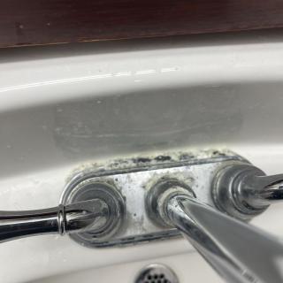 Close-up of a bathroom sink faucet with visible mold and grime.