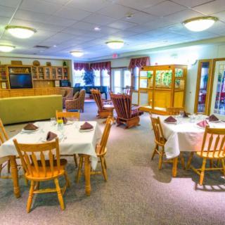 A cozy dining area with multiple tables set for a meal, featuring wooden chairs and decor.