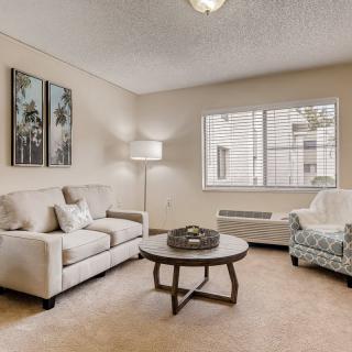 A cozy living room with neutral tones featuring a sofa, armchair, and coffee table.