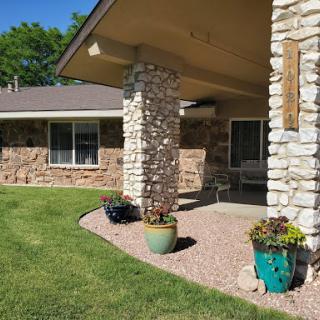 A cozy home entrance featuring stone columns and colorful planters.