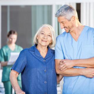 A nurse provides assistance to a smiling elderly woman.