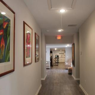 A brightly lit hallway adorned with framed artwork on the walls.