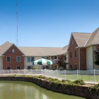 A residential building with a pond and a fence in the foreground.