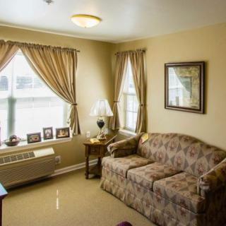 A cozy living room with a patterned sofa, accented by elegant curtains and a side table with a lamp.