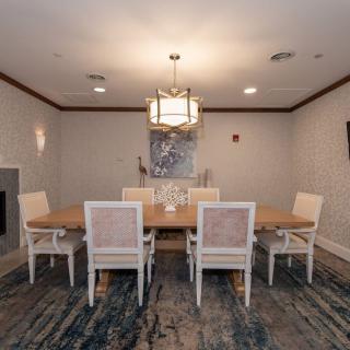 A stylish dining room featuring a large wooden table with six chairs, a modern chandelier, and artistic wall decor.