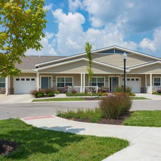 A suburban residential building surrounded by a landscaped front yard and clear skies.