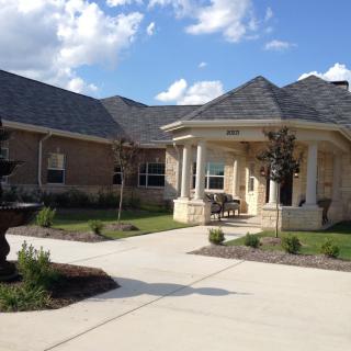 A beautiful residential house with a landscaped yard and driveway under a partly cloudy sky.