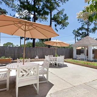 A sunny patio area with tables, chairs, and umbrellas next to a gazebo.