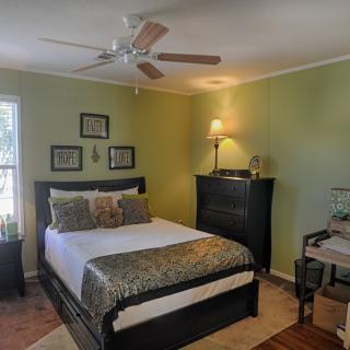 A cozy bedroom with green walls, featuring a double bed and ceiling fan.