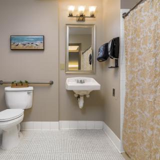 A well-lit bathroom featuring a toilet, sink, shower curtain, and modern amenities.