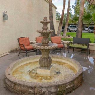 A stone fountain in a patio area with seating.