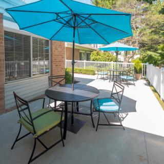 A cozy outdoor seating area featuring colorful umbrellas and a dining table, perfect for enjoying sunny days.