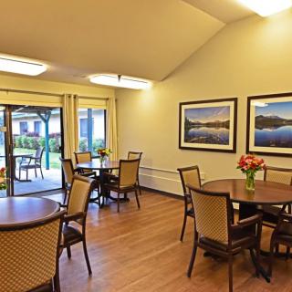 A cozy dining area with tables, chairs, and decorative artwork on the wall.