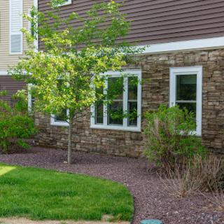 A beautiful residential building with a stone facade, featuring lush greenery and well-maintained landscaping.