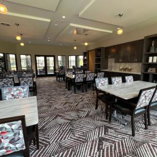 A modern dining room with patterned carpeting and stylish chairs arranged around tables.