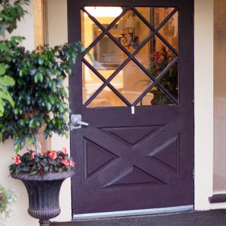 A decorative entrance featuring a door with glass panels and a planter filled with flowers.