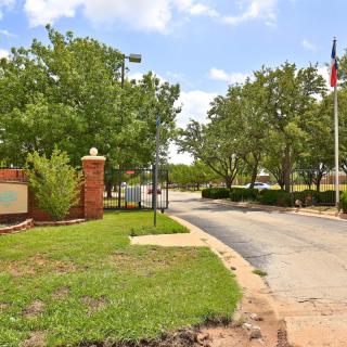 Entrance to a facility with a welcoming sign, surrounded by trees and flags.