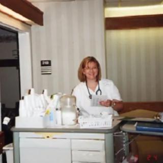 A nurse standing by a medical cart in a hospital setting.