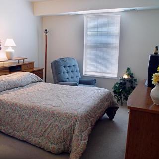 A cozy bedroom with a single bed, chair, and natural light from a window.