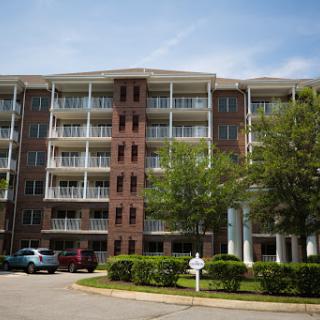A modern residential building featuring multiple balconies and surrounded by greenery.