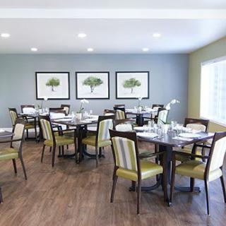 A well-arranged dining room with several tables and chairs, decorated with framed artworks on the wall.