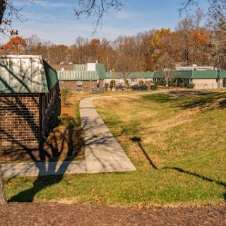 A serene view of a park with pathways and buildings surrounded by autumn foliage.
