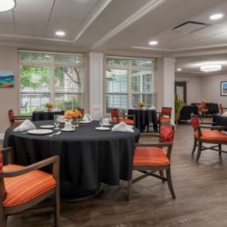 A modern dining room with elegantly set tables and bright chairs.