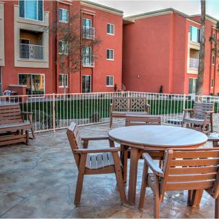 A patio area with wooden furniture, overlooking a brick apartment complex.