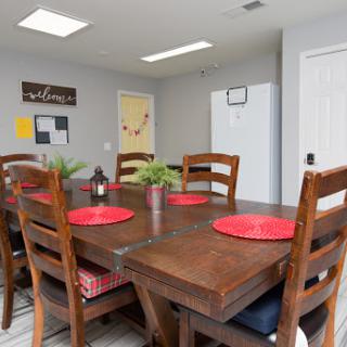 A cozy dining area featuring a wooden table with red placemats and comfortable chairs, complemented by decorative elements.