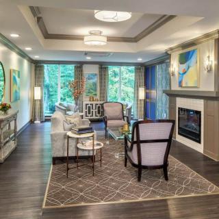 A modern living room with stylish furniture, a fireplace, and large windows overlooking greenery.