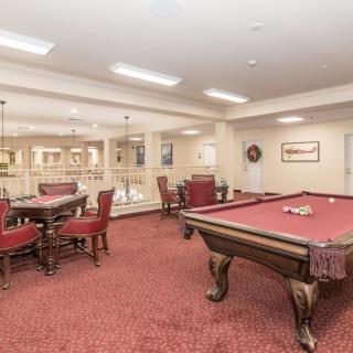 A cozy game room featuring a pool table and comfortable seating areas on a red carpeted floor.