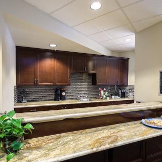 A modern kitchen interior with dark wood cabinets and a marble countertop.