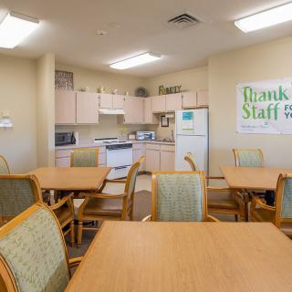 An office break room with tables, chairs, and kitchen appliances.