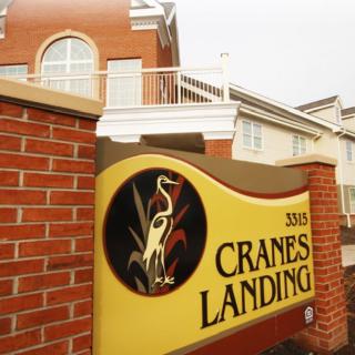 A sign for Cranes Landing in front of a building.