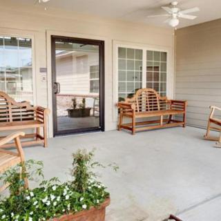 A cozy porch with wooden furniture and ceiling fan.