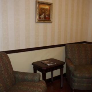 A cozy living room corner featuring two armchairs, a small table, and a framed painting on the wall.