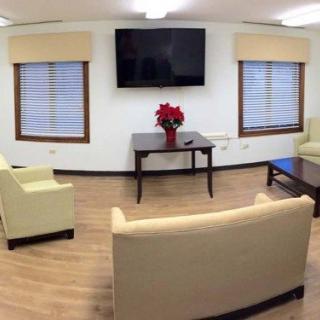 A cozy living room with modern furnishings, featuring a TV, sofas, coffee tables, and decor elements like poinsettia flowers.