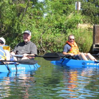 Group of people kayaking on a river surrounded by lush greenery.