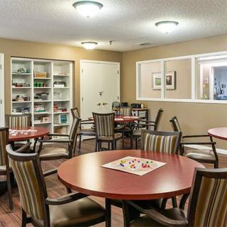 A cozy dining area with round tables and a bookshelf in the background.