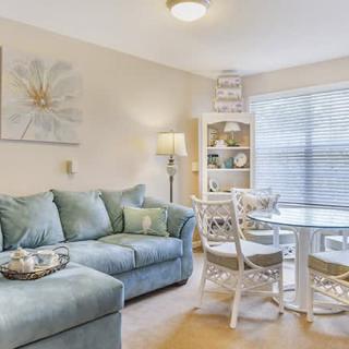 A cozy living room with a blue sofa and dining area, accentuated by natural light and elegant decor.