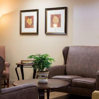A cozy living room with comfortable chairs and framed artwork on the wall.