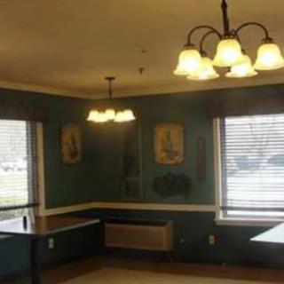 A cozy dining room with large windows, wall art, and a chandelier.