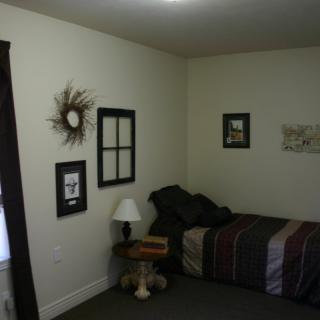 A minimalist bedroom with a single bed, wall art, and a bedside lamp.