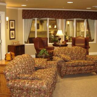 Cozy living room with patterned sofas and chairs, a lamp, and window curtains.