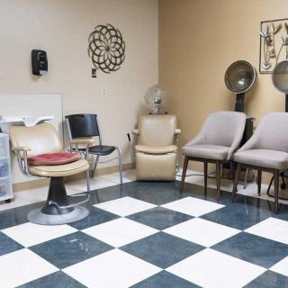 A hair salon waiting area featuring various chairs and classic decor.