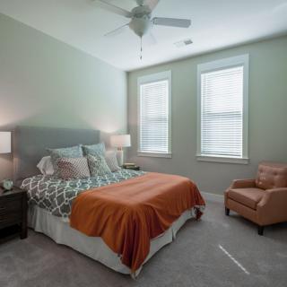 Cozy bedroom with a comfortable bed, stylish lamp, and armchair by the window.