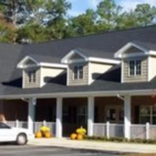 A residential-style building with a dark roof and a parked car in front.